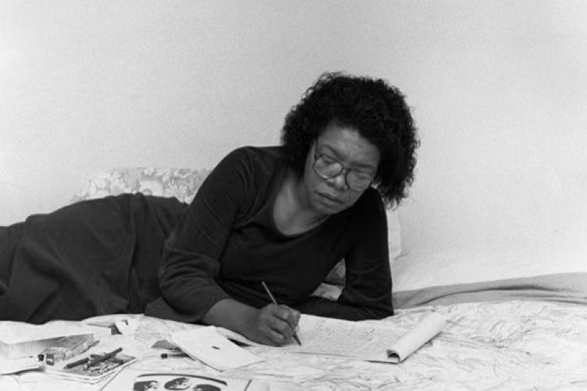 African woman writing on a bed.