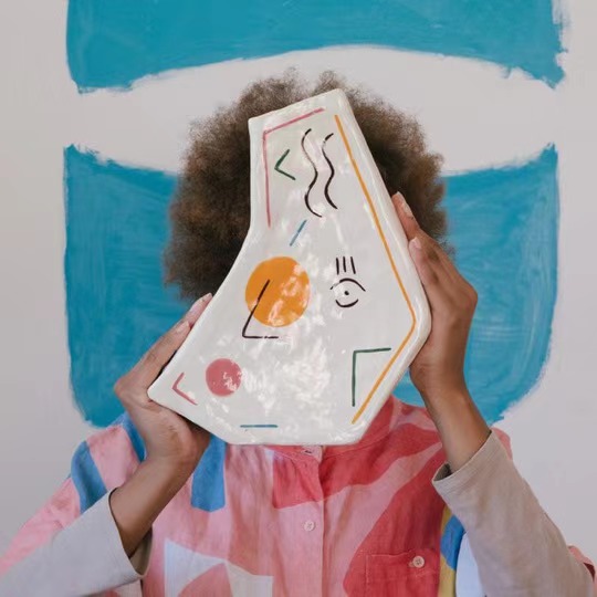 a woman holding up an art piece