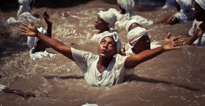 African women in a water body praying