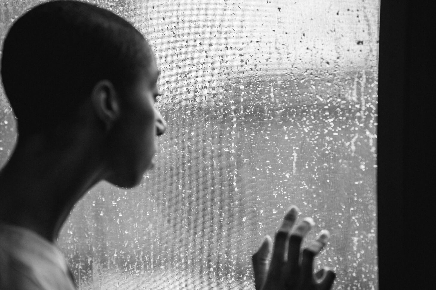 an African woman staring outside her window.